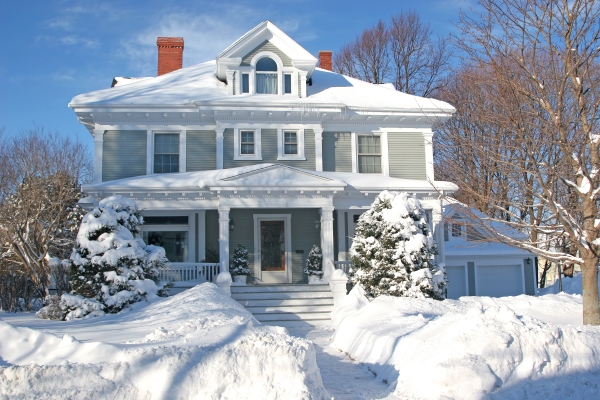 Large, older residential home covered with a lot snow