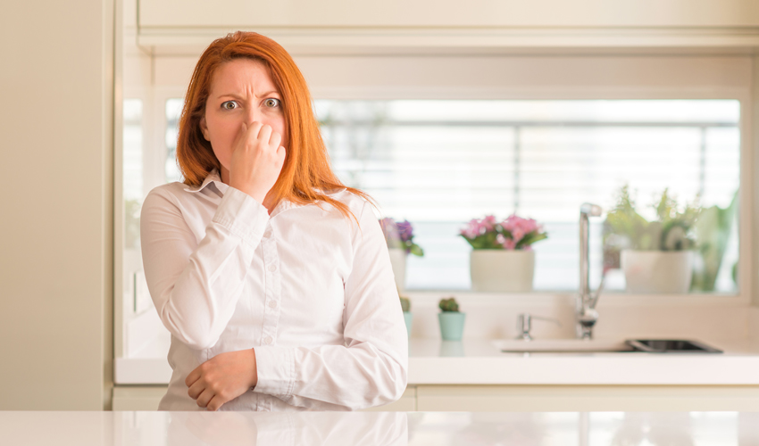Woman plugging her nose because of a musty smell in her house