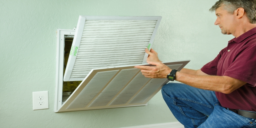 Professional AC repair man installing a new air filter in house AC unit.