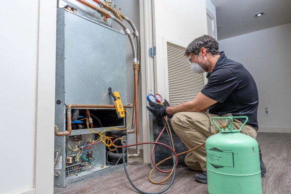 Technician wearing safety goggles and mask checking refrigerant charge on HVAC system